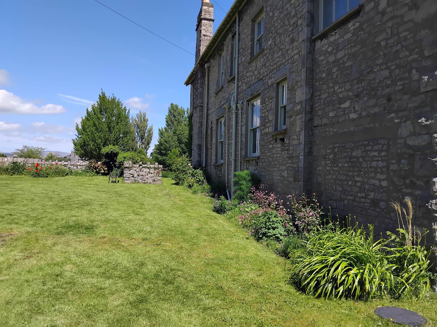 The lawn and flowering borders beside the stone walls of Olrig Bank