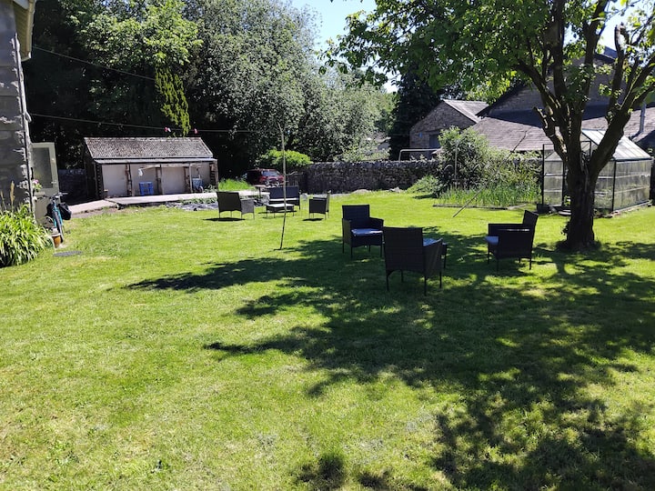 The wide lawn at Olrig Bank with mature trees and outdoor seating