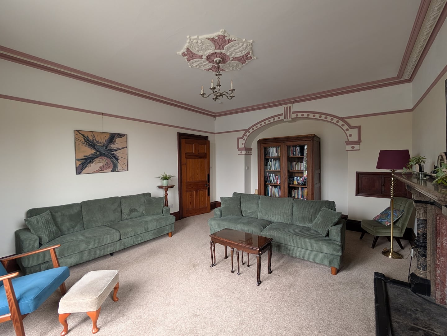 The main-house lounge with green sofas, period plasterwork and fireplace